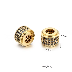 Détail macro d'une perle cylindrique dorée de 0,6 cm avec pavé de zircons noirs