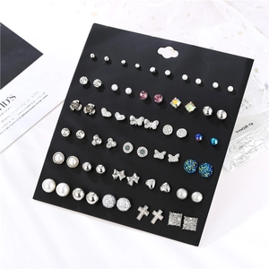 Detailed close-up of 30 pairs of assorted geometric metal pearl and crystal stud earrings