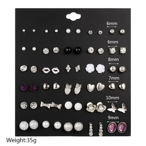Close-up of 36 pairs earring set featuring pearls, rhinestones and heart shapes on black card