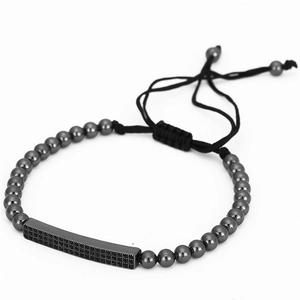 Détail du bracelet en perles noires avec barre en métal sertie de zircons et cordon tressé
