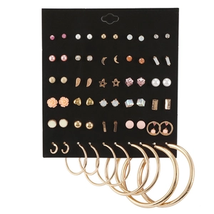 Macro view of 30 pairs assorted gold earrings set with pearls and rhinestones on black card