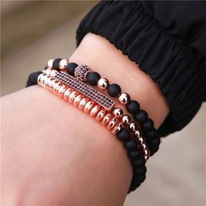 Gros plan d'un ensemble de trois bracelets en or rose et perles noires portés au poignet