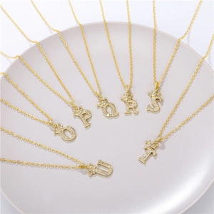Golden crown initial necklaces O-U with sparkling zircon on a ceramic jewelry tray
