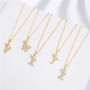 Close-up of gold crown letter pendants V-Z with pavé cubic zirconia on minimalist stand
