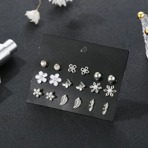 Detalle de 9 pares de pendientes plateados con motivos de flores y mariposas