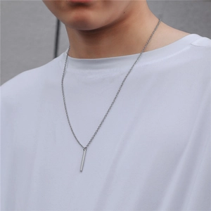 Close-up of a minimalist vertical rectangular bar pendant on a male model with white tee