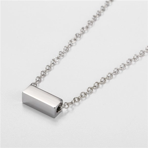 Macro shot of silver stainless steel minimalist rectangular bar pendant on cable chain