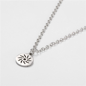 Detailed macro shot of a round sunburst cutout pendant on a stainless steel link chain
