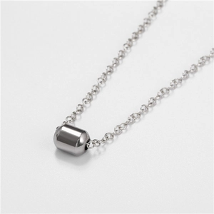 Macro shot of minimalist solid cylindrical pendant in polished silver stainless steel