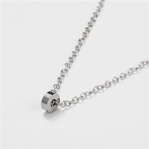 Close-up of a minimalist stainless steel cylinder pendant on a fine link chain necklace