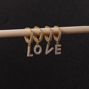 Detailed close-up of gold-plated LOVE letter hoop earrings with sparkling zircon inlay