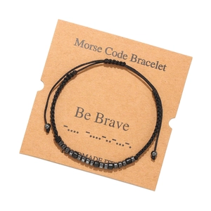 Detail of Morse code bracelet with black beads and brave message on kraft card