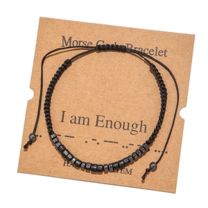 Detail of Morse code bracelet with black beads on a card reading I am Enough