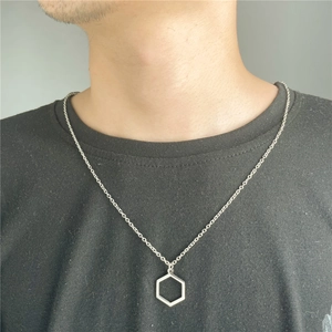 Close-up of a silver stainless steel necklace with a hollow hexagon pendant on a black shirt