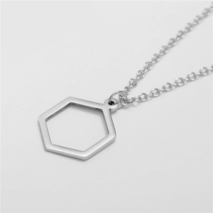 Macro shot of a silver polished hexagonal hollow pendant necklace on a plain white background