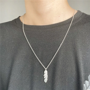 Close-up of a silver feather pendant necklace on a model with a stainless steel O-chain