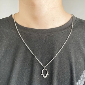 Macro shot of silver Hamsa hand pendant with cut-out design on a male model