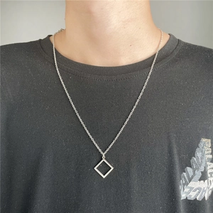 Detailed view of a silver hollow square geometric pendant necklace on a black shirt