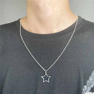 Detailed close-up of a minimalist hollow star pendant on a silver-toned chain worn by a model
