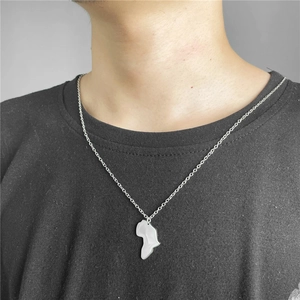 Close-up of a minimalist silver Africa map pendant necklace worn by a model on a black tee