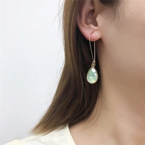 Eleganti orecchini a goccia dorati con cristalli verde chiaro indossati da una modella