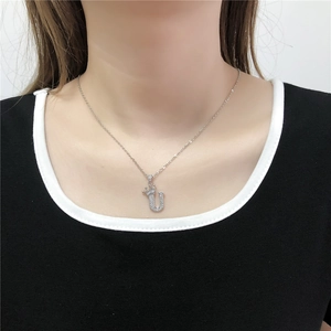 Detail van zilveren kroon letter U hanger met zirkonia op een fijne geschakelde ketting