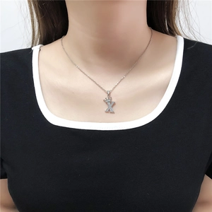 Detail van zilveren letter X hanger ketting met kroon en zirkonia op een model