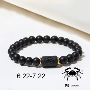 Close-up of matte black agate beads bracelet featuring a Cancer zodiac sign charm