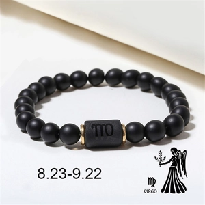 Detailed view of matte black onyx Virgo zodiac bracelet with golden metal accents