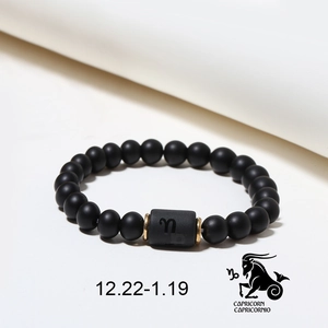 Detail of matte black onyx Capricorn bracelet with gold spacers and zodiac symbol cylinder