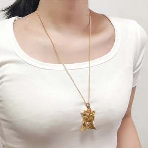Detail of golden geometric star pendant necklace shown on a model with brushed finish