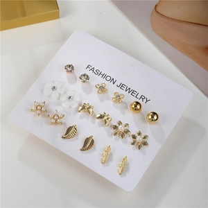 Detalle de set de 9 pares de pendientes con perlas, flores, estrellas y mariposas doradas