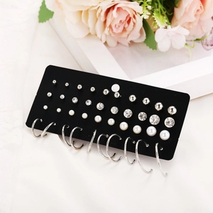 Detalle de set de 20 pares de pendientes con perlas y circonitas en tarjeta negra