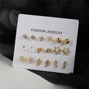 Set de 9 pares de pendientes con perlas, flores doradas, mariposas y estrellas en cartón