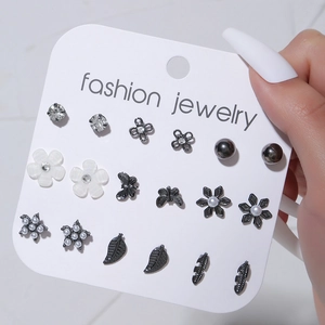 Detalle del set de 9 pares de pendientes con perlas y flores sobre cartón blanco