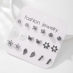 Detalle del set de 9 pares de pendientes plateados con perlas y diseños de mariposa