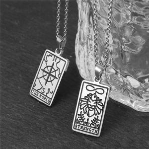 Gros plan artistique de colliers tarot avec gravures Le Monde et La Force en acier