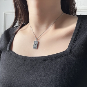 Gros plan d'un collier tarot argenté avec pendentif « The Sun » sur une chaîne en acier