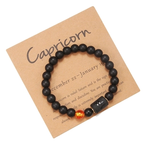 Primer plano de pulsera Capricornio de cuentas de ágata negra mate en tarjeta kraft