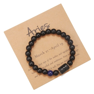 Detalle de la pulsera Aries con cuentas negras mate y piedra azul en tarjeta de cartón