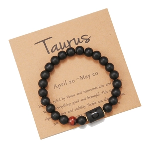 Detalle de pulsera zodiaco Tauro con cuentas negras y ojo de tigre rojo sobre tarjeta kraft