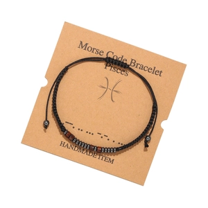 Vue détaillée du bracelet code Morse Poissons avec perles en bois noir sur carte kraft