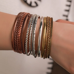 Detailopname van gemengde metalen armbanden met goud, zilver en roségoud getextureerde lagen
