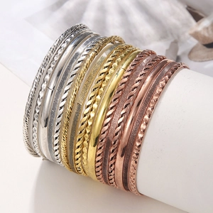 Detailweergave van 16 gemengde metalen armbanden met texturen op een witte standaard