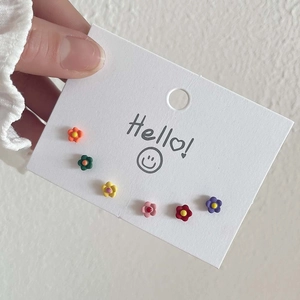 Detailansicht bunter Blumenohrstecker auf einer Displaykarte mit Smiley-Gesicht