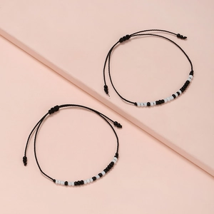 Macro detail of two-piece Morse code beaded bracelets on a soft pink geometric stand