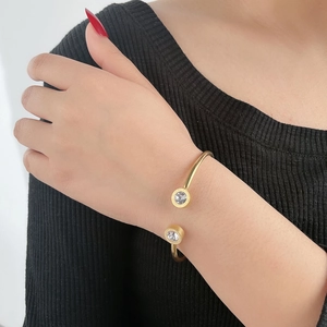 Vista detallada del brazalete en C dorado con números romanos y piedras de circón
