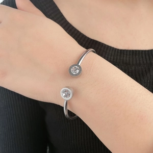 Detalle de brazalete plateado en forma de C con números romanos y piedras de circonita