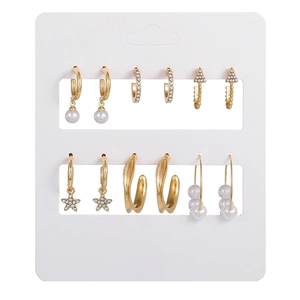 Dettaglio macro di un set di 6 paia di orecchini dorati con perle finte e strass scintillanti
