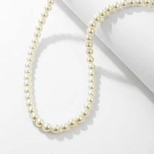 Close-up of elegant white glass pearl necklace with smooth luster on minimalist background